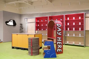 A colorful retail shop interior with cardboard displays, painted shelves, and metal shelving.