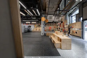 Modern industrial-style climbing wall with concrete and wood accents at a fitness center.
