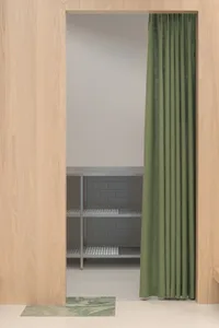 A minimalist kitchen with a green curtain and metallic shelving.