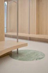 Modern minimalist interior with a curved wooden bench and a round marble floor inset