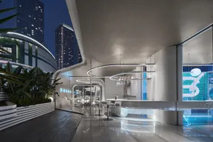 A sleek, modern hotel bar with concrete and glass materials, featuring a circular bar counter, potted plants, and contemporar