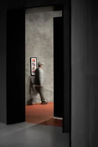 A modern interior with concrete walls and a person walking in a hallway.