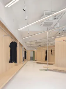 An empty, modern retail store with wooden interior and clothing racks.