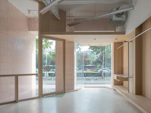 Modern retail storefront interior with wooden deck, glass walls, and tiled walls looking out onto a street view.