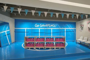 Shopping center retail interior with metallic surfaces, plastic baskets, and blue walls.