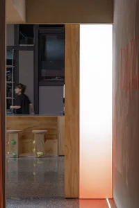 A minimalist commercial office space with wood accents, featuring a frosted glass wall and industrial black furniture.