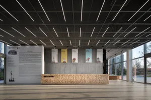 Modern office lobby with concrete walls and floor, featuring design banners and a reception desk.