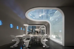 A modern restaurant with glass walls and visible cityscape through the windows.