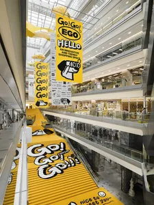 Interior view of a modern shopping centre with a bright yellow plastic walkway.