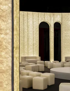 A modern seating arrangement with textured wall coverings, including white ottomans and seating.