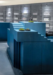 A retail space with blue wooden structures and green foliage displays.