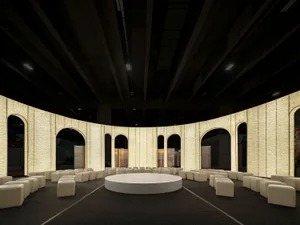 A conference room with industrial design elements, featuring a circular stage and concrete walls with arched openings.
