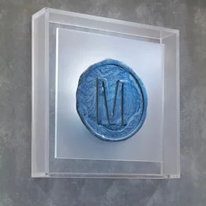 A minimalist design featuring a blue monogram on a ceramic surface.