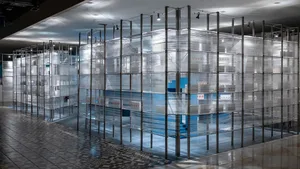 A minimalist exhibition space enclosed by transparent plastic sheets with a steel structure