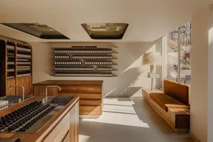 A minimalist storefront with wooden furniture and glass shelves.