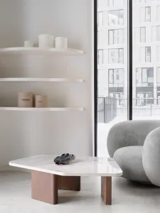 A minimalist living area featuring a white marble coffee table and gray upholstered sofa in front of a large window.