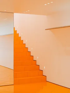 A minimalist staircase with orange tiles and white walls.