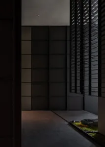 Modern interior corridor with concrete flooring, black glass walls, and black window shutters.
