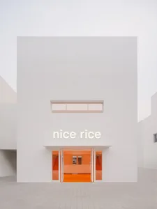 White concrete exterior of a minimalist restaurant with orange accents.