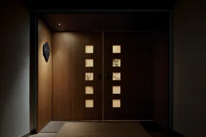 極簡室內空間，木質前門帶有幾何鏤空設計，背光照明。