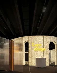 A minimalist interior with a textured, illuminated wall and a circular reception desk.