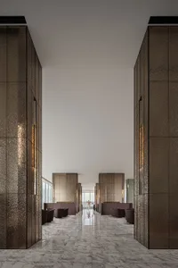 A modern hotel lobby featuring metallic-textured walls and marble floors.