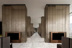 Modern lobby with metallic textured wall panels, white marble flooring.