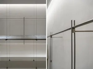 A minimalist metal shelf system supported by thin cables.