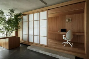 A modern home office featuring wooden walls, a white office chair, and a sliding shoji screen.