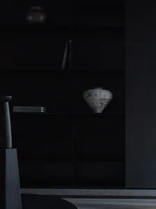 A modern black bookshelf with a ceramic vase on it.