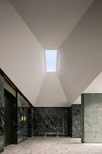 A modern lobby featuring marble floors and concrete walls.