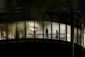 A modern residential interior featuring large glass windows with a dark exterior.