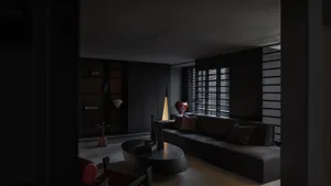 A minimalist living room with dark, sleek black furniture, a rug, and a light lamp.