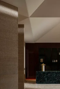 A modern lobby interior with a concrete wall and geometric ceiling design.