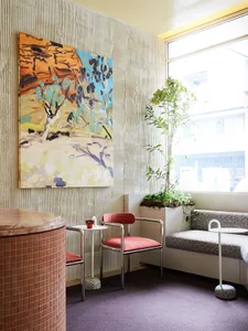 A sleek, modern coffee shop with metallic red plastic chairs and plants.