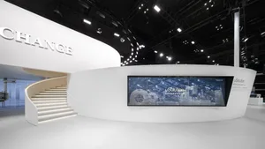 Modern minimalist exhibition design with a white circular wall and digital screen showcasing technology solutions.