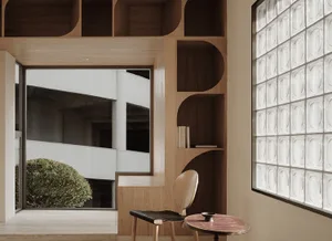 A minimalist interior design featuring wooden shelving and a glass block window.
