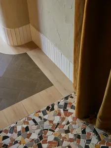Modern bathroom with terrazzo tile flooring, wooden walls, and white baseboard
