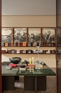 A modern bookstore display featuring wooden shelves with framed illustrations, glass candle holders, and books.