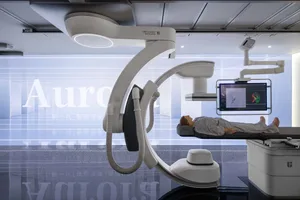 A medical device is shown in a hospital suite, featuring a patient on a bed and a display screen.