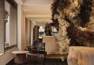 A hotel reception area featuring modern decor with dry flower arrangements, concrete elements, and comfortable seating.