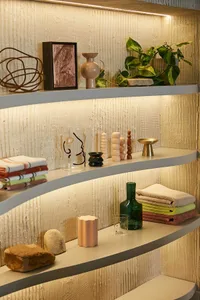 A modern interior with floating wooden shelves displaying various decorative items, including vases, candles, and plants.