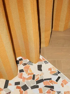 Modern interior design featuring a terrazzo floor with a mix of orange, black, and white stone chips.