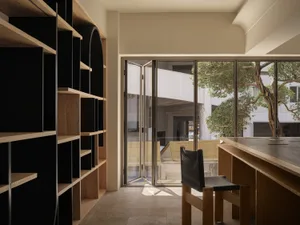 A modern library with wooden shelves and a wooden table with a black chair.