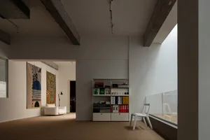 A modern living room with concrete walls, minimalist furniture, and large windows.