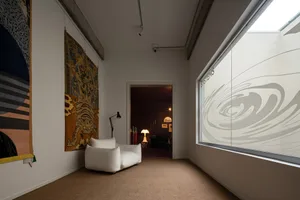 A modern living room featuring a white sofa and a large window with an abstract design.