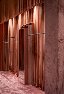 Modern retail space featuring velvet curtains and mirrored display with clothing racks.