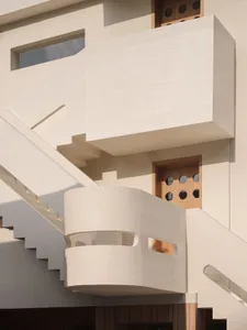 Modern concrete staircase with curved balustrades and white railings.