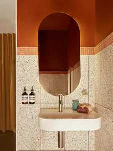 A modern bathroom featuring a sink, faucet, and orange wall with a rounded arch entrance.