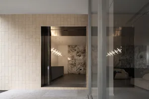 A modern industrial lobby with concrete and tile walls, featuring a minimalist design with geometric lighting fixtures.